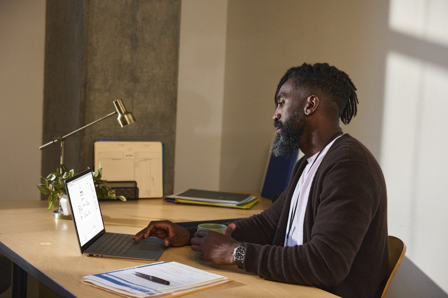 Um Educador está sentado em uma mesa e usa o Microsoft Copilot em um laptop.